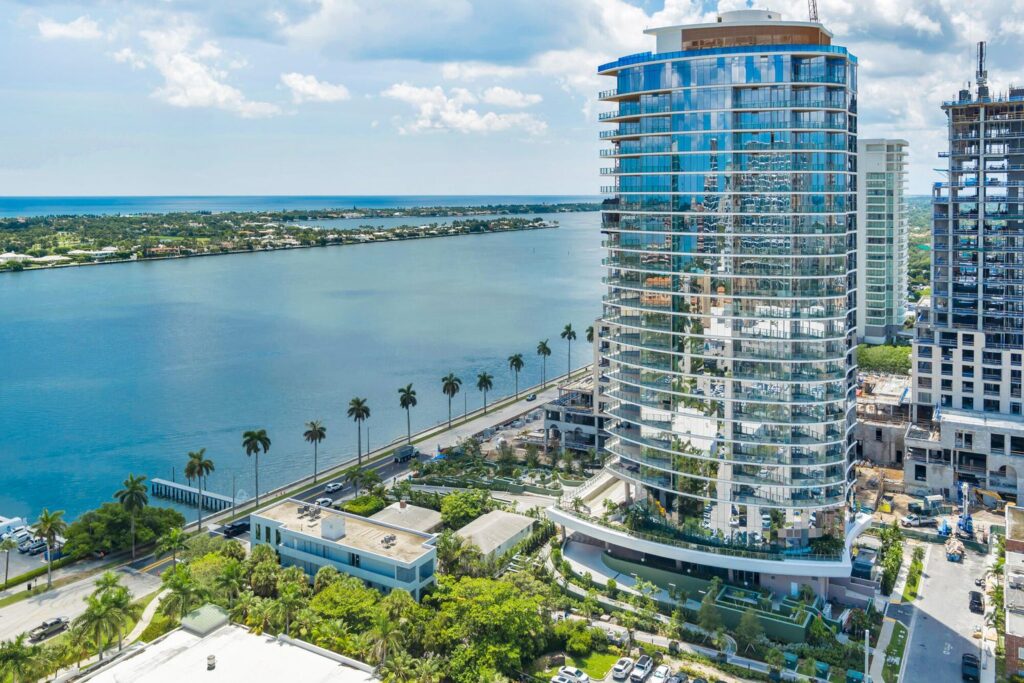 Modern waterfront glass high-rise with palm trees